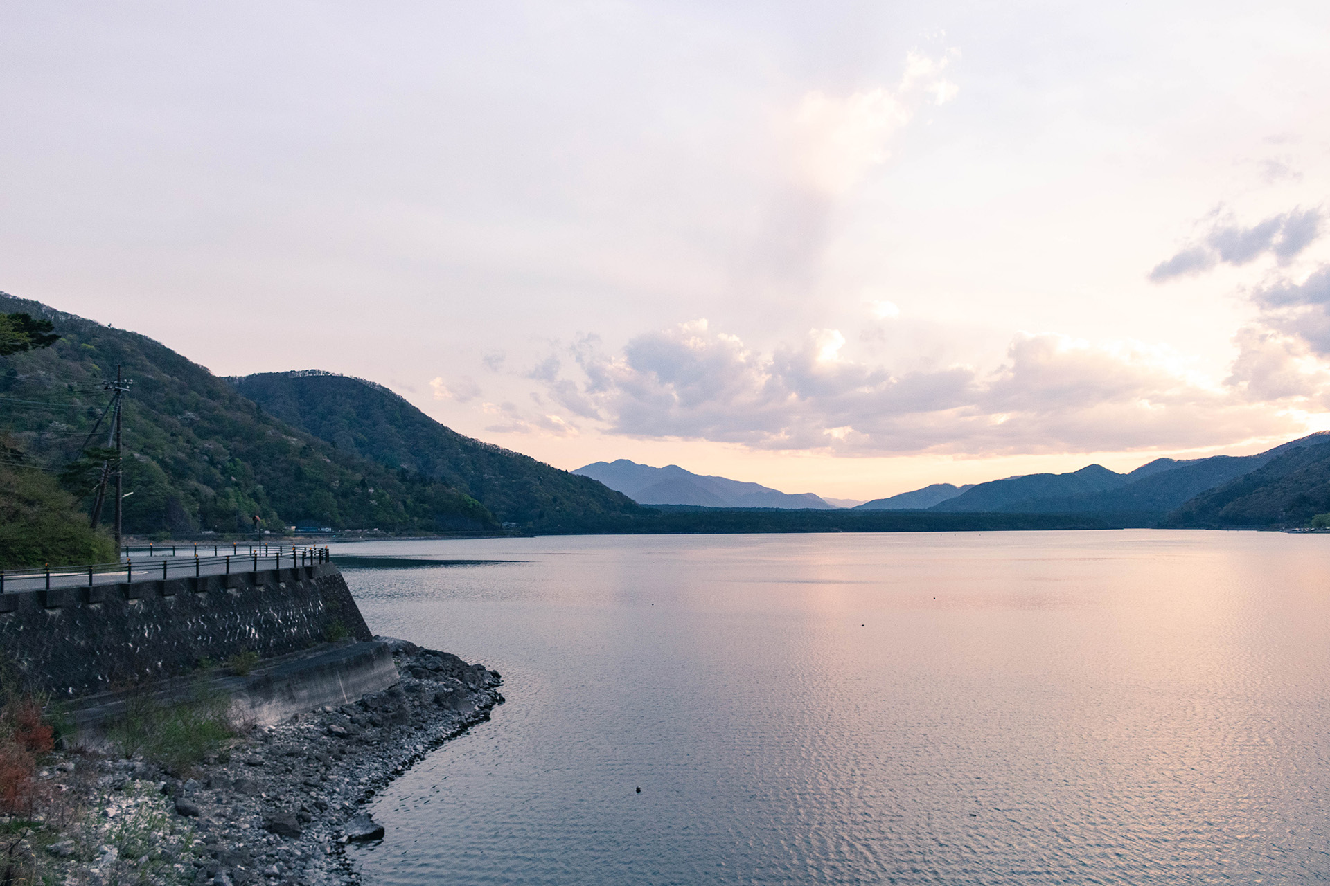 Golden hour view of a lake surrounded by mountains.